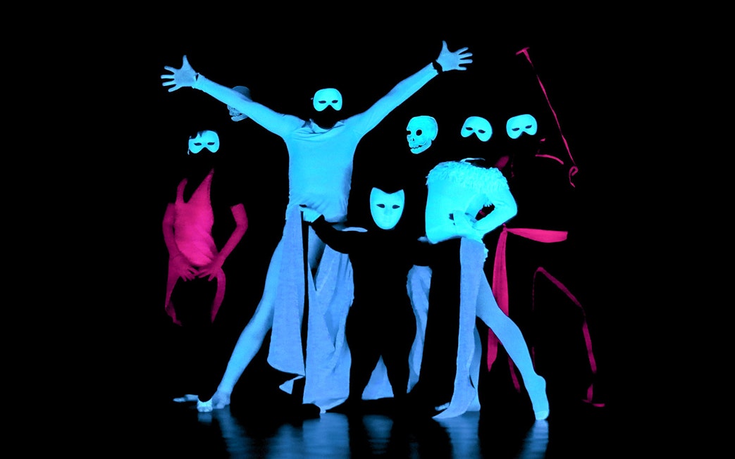 Performers in masks at a black light theatre show, Prague.