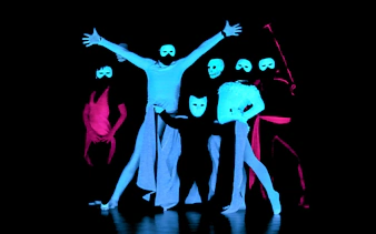 Performers in masks at a black light theatre show, Prague.