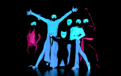 Performers in masks at a black light theatre show, Prague.