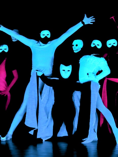 Performers in masks at a black light theatre show, Prague.
