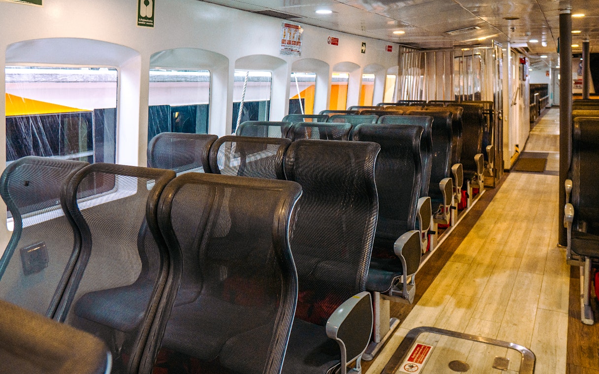 Interior seating of Singapore to Batam ferry with rows of black mesh seats.