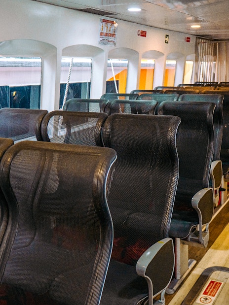 Interior seating of Singapore to Batam ferry with rows of black mesh seats.
