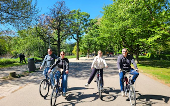 Cyclists enjoying a scenic ride through a park on the Amsterdam City Highlights Bike Tour.