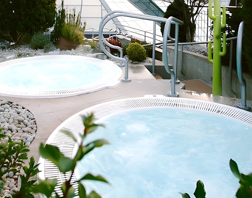 Solarium with jacuzzi at Caldea Spa, Andorra, featuring panoramic mountain views.