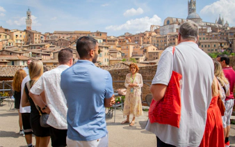 Tour group in Siena with guide, overlooking historic cityscape, part of Tuscany Grand Tour.