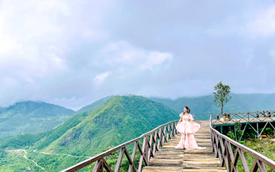 Wooden walkway at O Quy Ho Fairy Heaven Gate, Sa Pa, with a person in traditional attire.