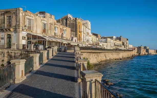 Siracusa waterfront view with guided walking tour group on Ortigia Island.