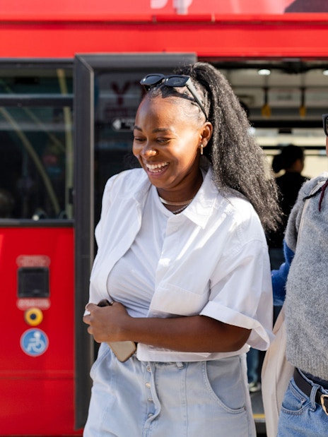Women smiling as they exit a red hop-on hop-off bus.