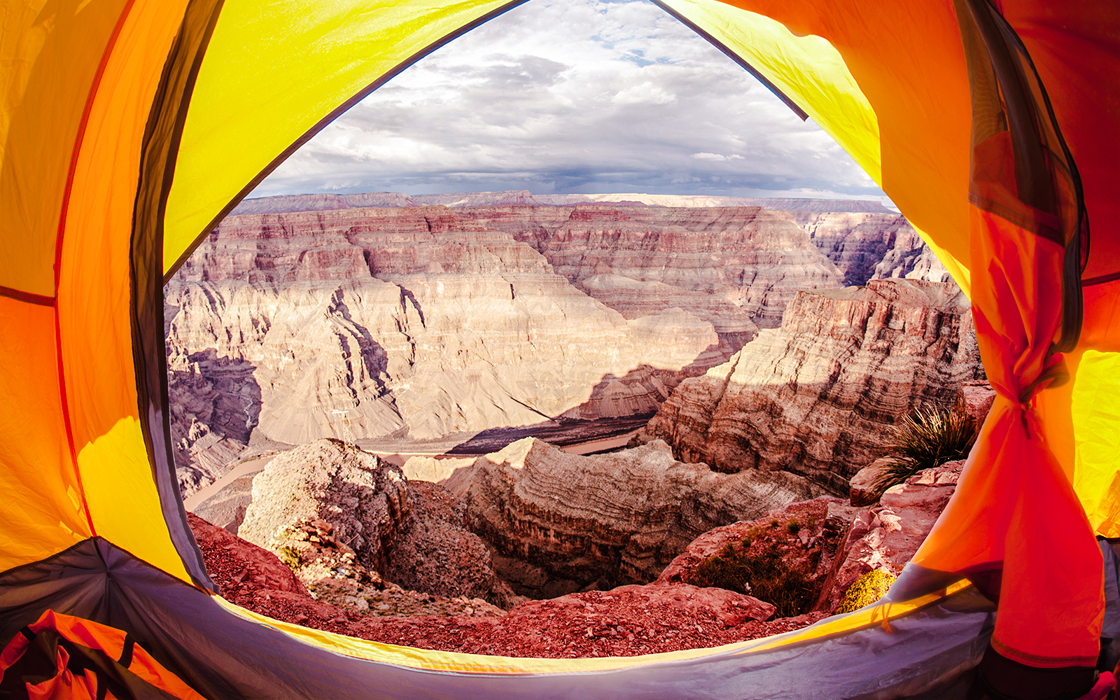 Open tent with view of Grand Canyon cliffs and sky.