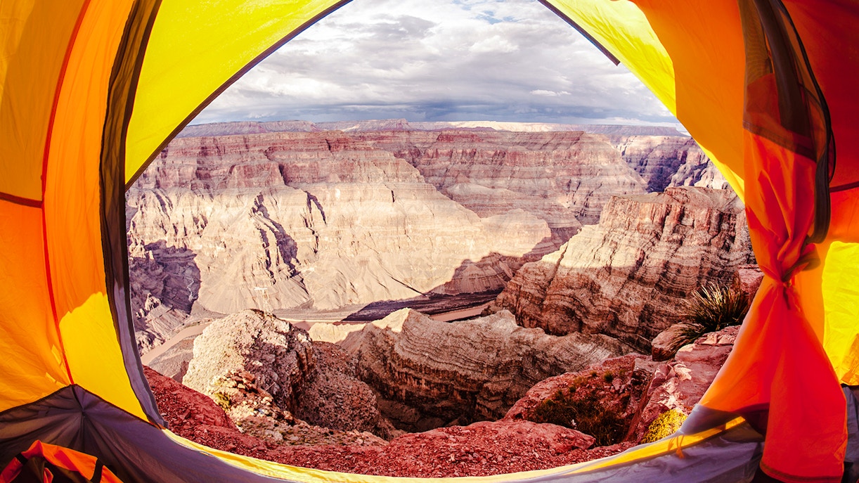 Open tent with view of Grand Canyon cliffs and sky.