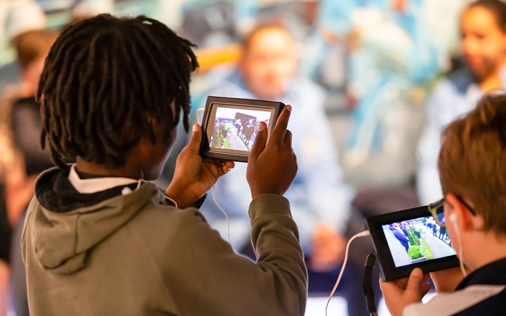 Visitors using tablets during Manchester City Stadium tour.