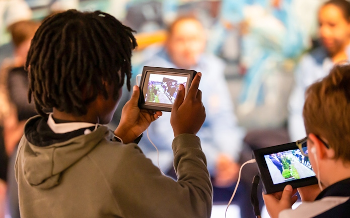 Visitors using tablets during Manchester City Stadium tour.