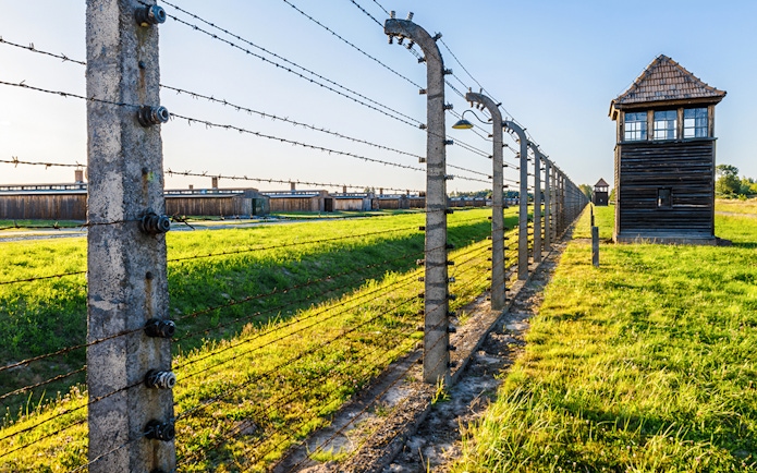 Barbed wire fence and watchtower at Auschwitz Birkenau, Auschwitz II barracks in Poland.