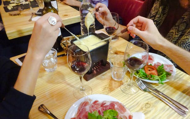People enjoying cheese fondue with wine at Paroles de Fromagers in Paris, France.