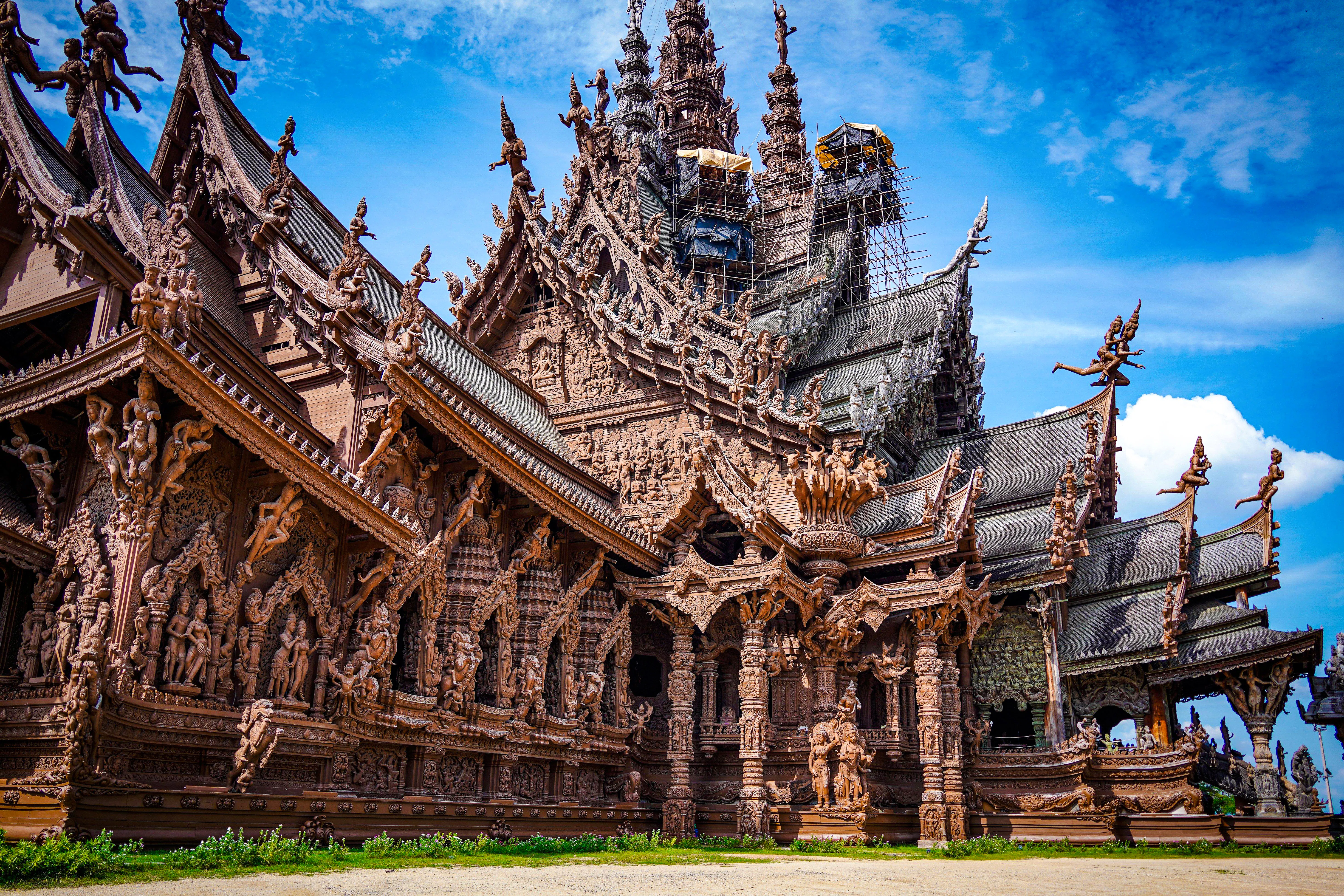 Sanctuary of Truth's intricate wooden carvings under blue sky, Pattaya city tour.