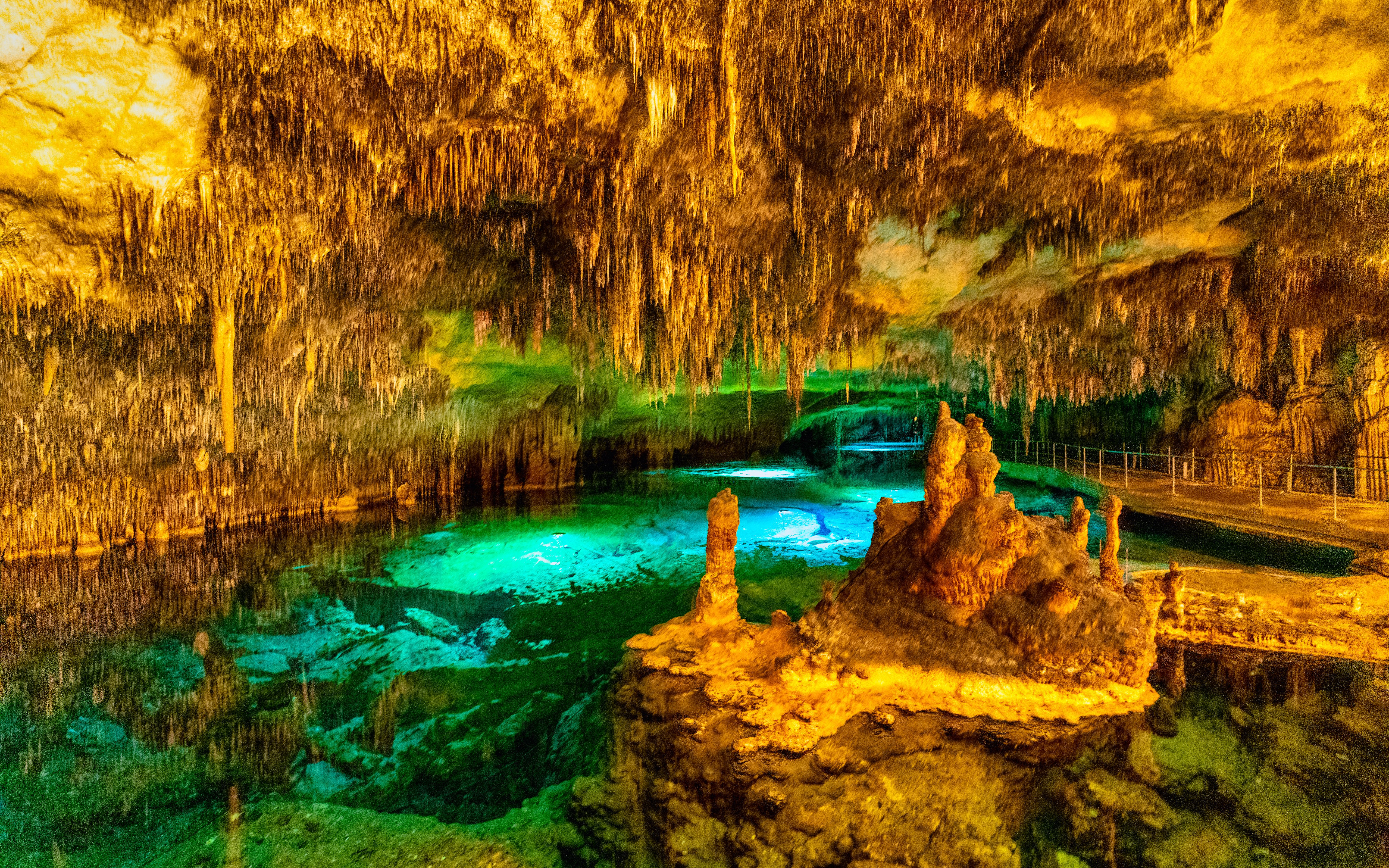 Stalactites and stalagmites inside Drach Caves with illuminated underground lake.