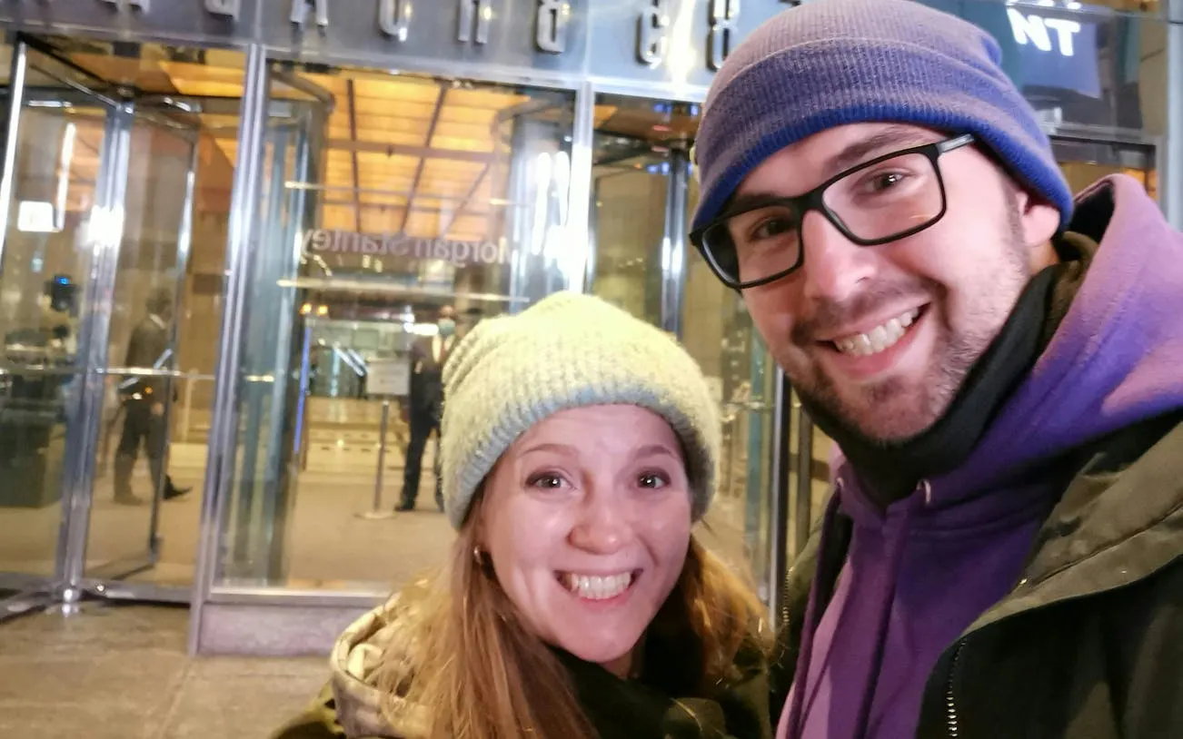 Couple smiling outside a New York City building during a self-guided superhero exploration game.