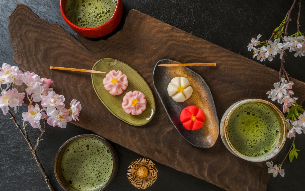 Matcha tea with traditional Japanese wagashi sweets and cherry blossoms.