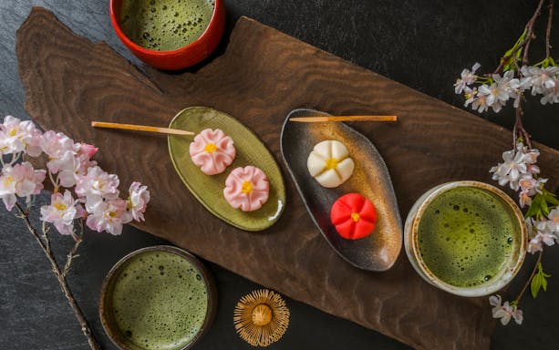 Matcha tea with traditional Japanese wagashi sweets and cherry blossoms.