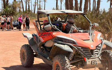 Buggy ride through Marrakech Palm Oasis with group in background.