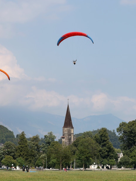 Paragliders soaring over Interlaken with church spires and mountains in the background.