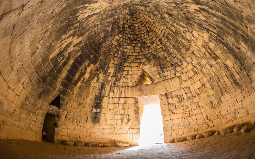Interior of ancient Greek tomb in Mycenae, Peloponnese, Greece, with stone dome and entrance.