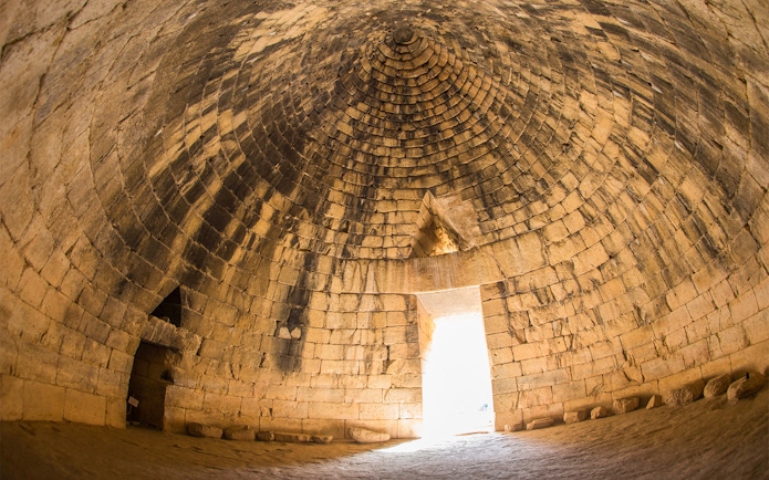 Interior of ancient Greek tomb in Mycenae, Peloponnese, Greece, with stone dome and entrance.