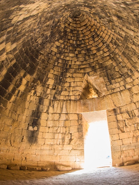 Interior of ancient Greek tomb in Mycenae, Peloponnese, Greece, with stone dome and entrance.