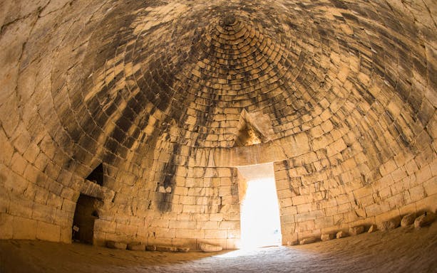 Interior of ancient Greek tomb in Mycenae, Peloponnese, Greece, with stone dome and entrance.