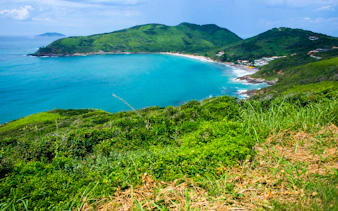 Coastal view of José Gonçalves beach in Búzios, Rio de Janeiro, surrounded by lush green hills.