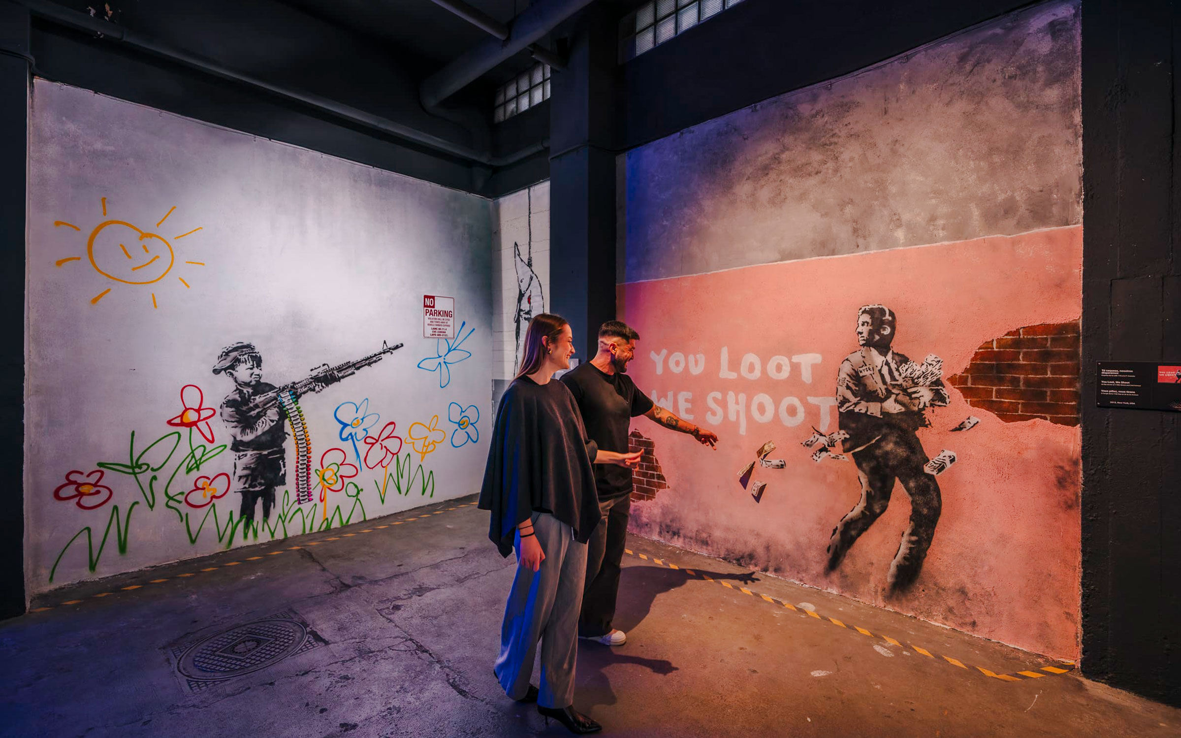 Visitors viewing Banksy murals at Banksy Museum Madrid, featuring colorful graffiti and social commentary.