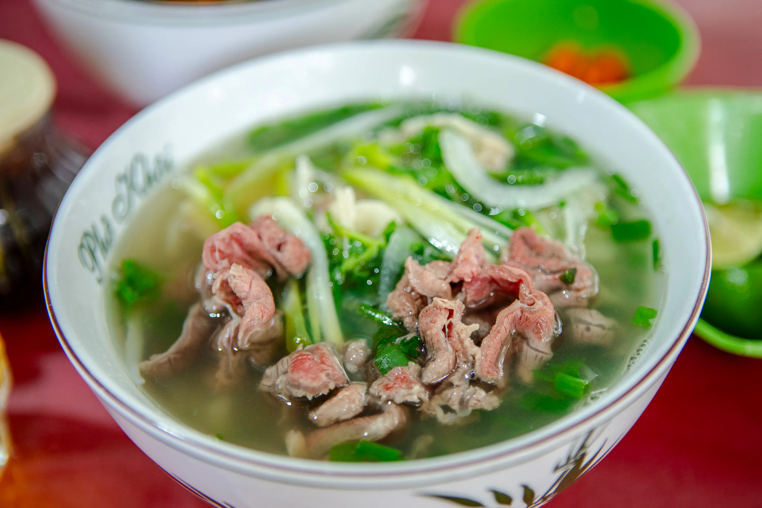 Bowl of Vietnamese pho with beef and herbs, part of Hanoi food tour.