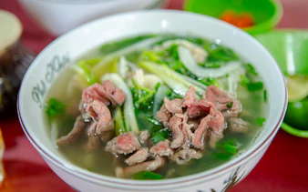 Bowl of Vietnamese pho with beef and herbs, part of Hanoi food tour.