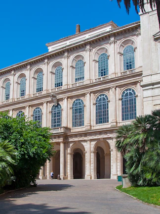 Galleria Corsini facade with arched windows and lush greenery in Rome, Italy.