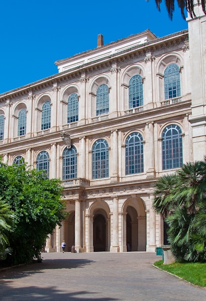 Galleria Corsini facade with arched windows and lush greenery in Rome, Italy.