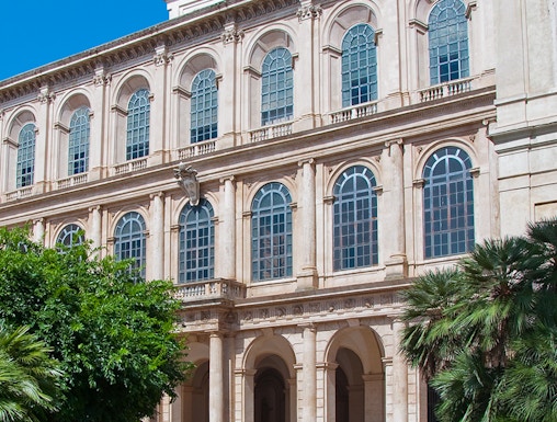 Galleria Corsini facade with arched windows and lush greenery in Rome, Italy.