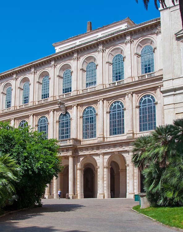 Galleria Corsini facade with arched windows and lush greenery in Rome, Italy.