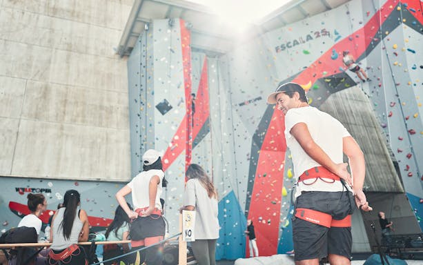 Participants preparing for a bridge climbing experience at an indoor climbing wall.