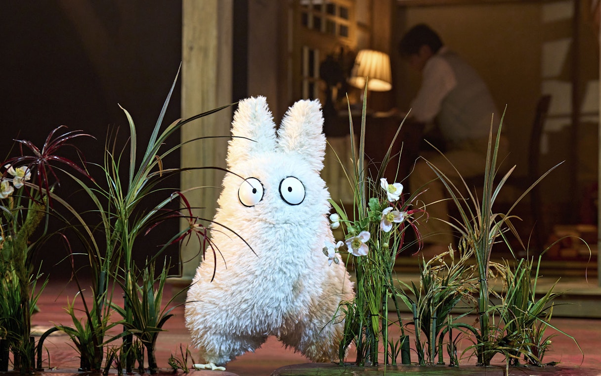 Furry creature on stage at My Neighbour Totoro West End show, surrounded by plants.
