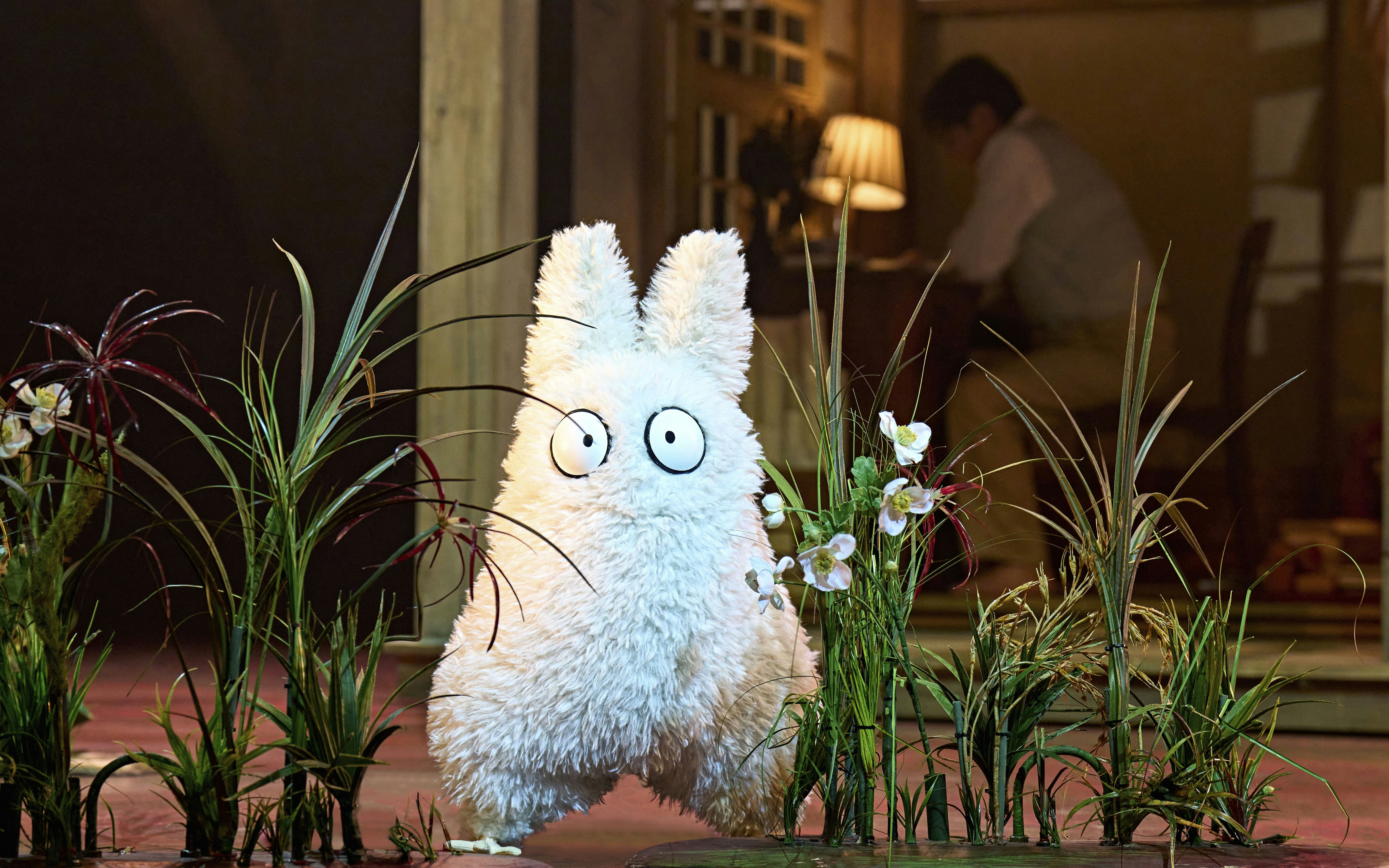 Furry creature on stage at My Neighbour Totoro West End show, surrounded by plants.