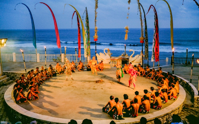 Kecak and Fire Dance performance at Melasti Beach with ocean backdrop.