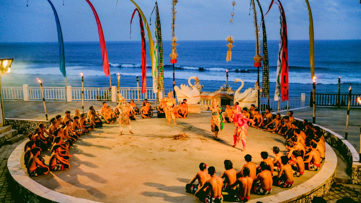 Kecak and Fire Dance performance at Melasti Beach with ocean backdrop.