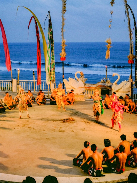 Kecak and Fire Dance performance at Melasti Beach with ocean backdrop.