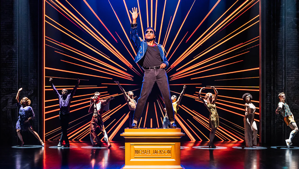 Performer on stage with dancers in MJ The Musical.