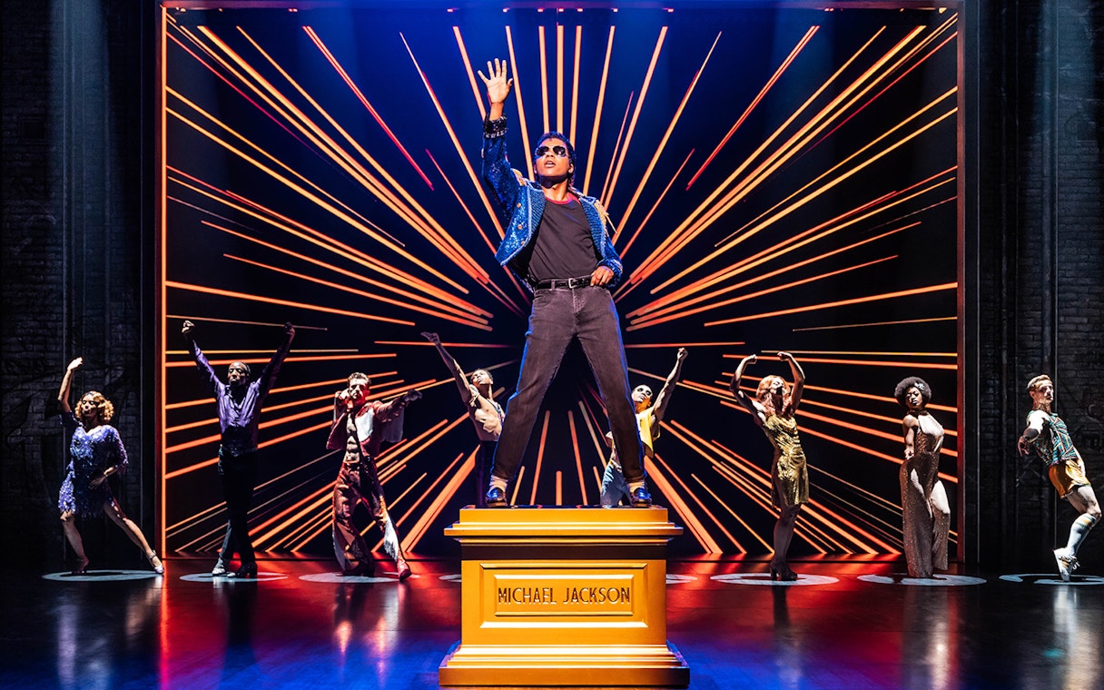 Performer on stage with dancers in MJ The Musical.