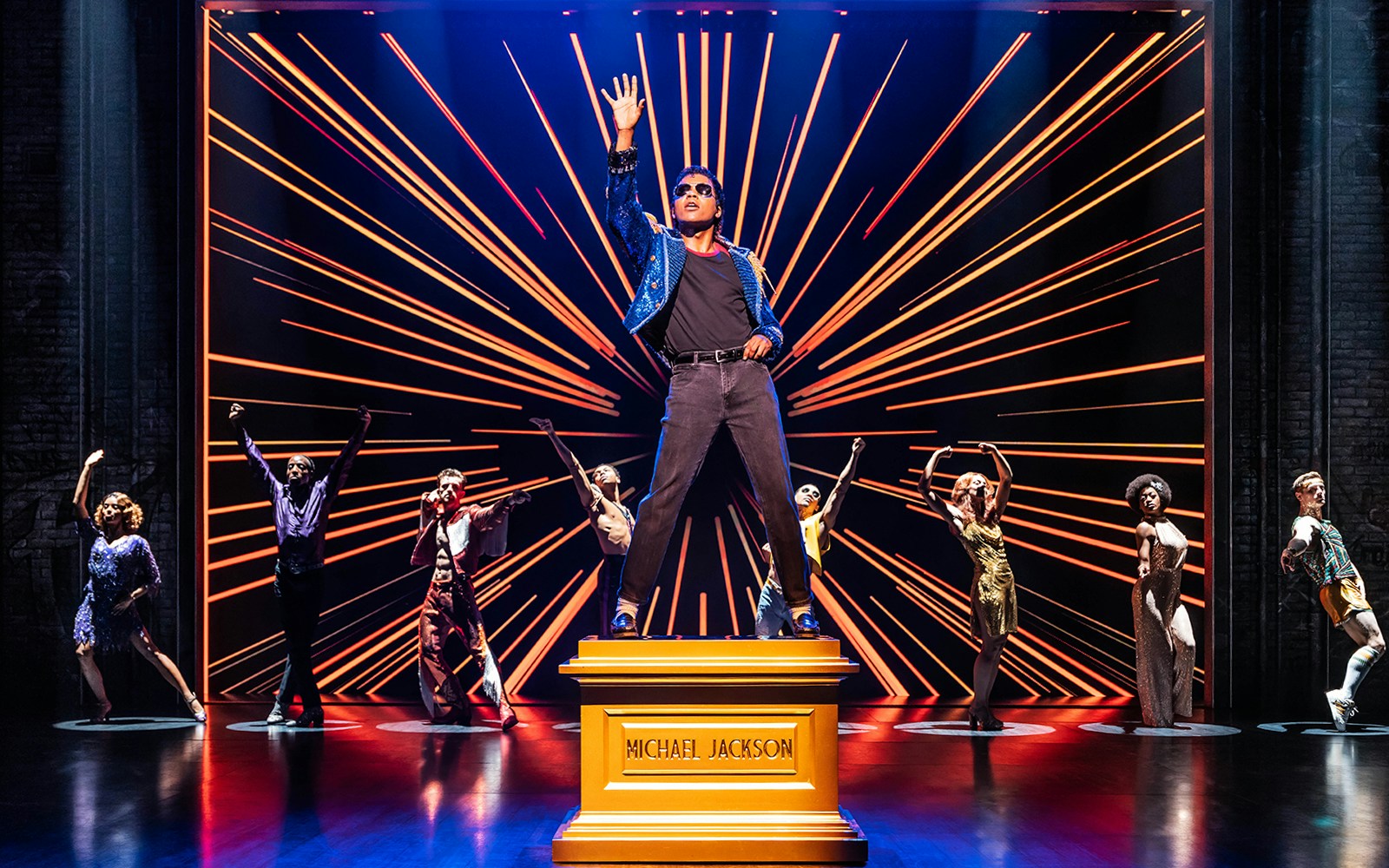 Performer on stage with dancers in MJ The Musical.