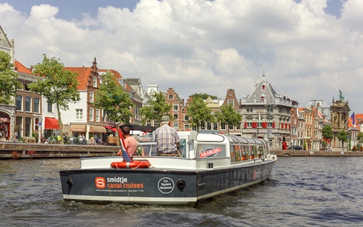Canal cruise boat on Haarlem's scenic waterways with historic buildings in the background.