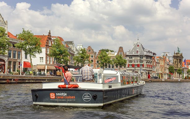 Canal cruise boat on Haarlem's scenic waterways with historic buildings in the background.