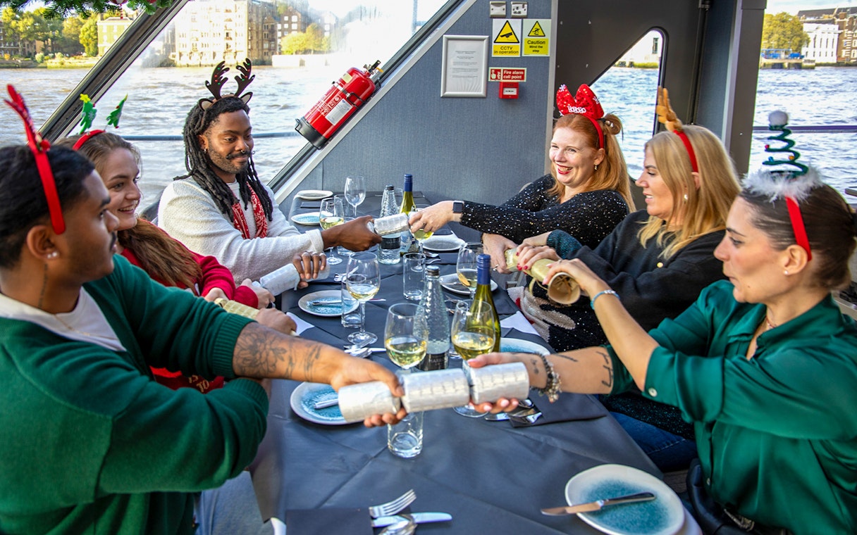 Guests pulling Christmas crackers on Thames River Cruise lunch party.
