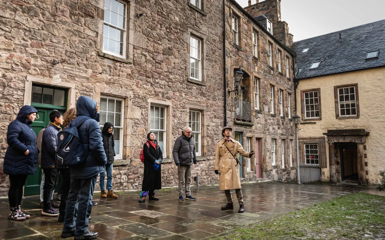 Tour group exploring historical buildings in Edinburgh with a guide.